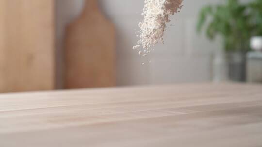 在木桌上缓慢地撒面粉