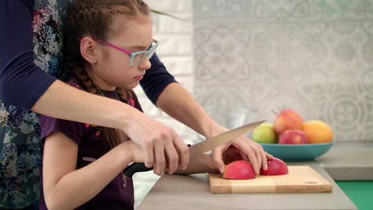 女人帮助孩子切苹果片