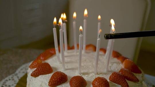 无法辨认的人用打火机点燃生日蛋糕蜡烛。