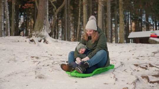 母亲和婴儿在树林中的雪橇体验