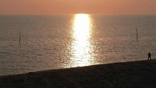 一个人走在夕阳照耀下的沙滩上