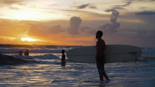 日落下海滩冲浪者手持中景视频素材模板下载