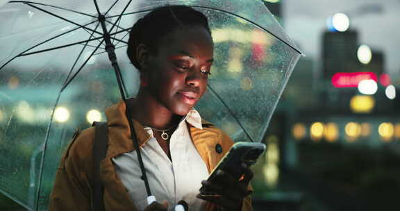 晚上的黑人女性，城市里的智能手机和雨伞，