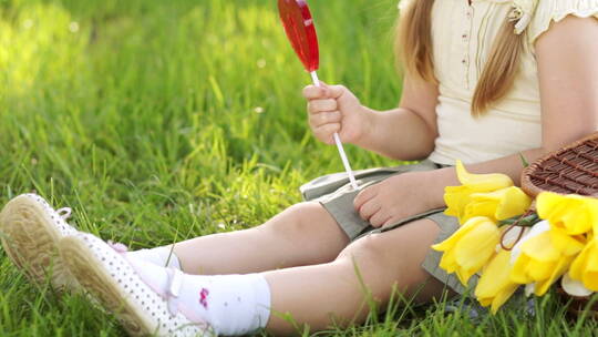 女孩坐在草地上吃棒棒糖