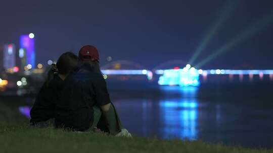 两个女孩坐在江边看夜景