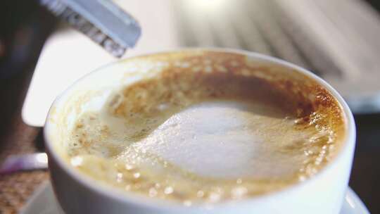 特写往咖啡中加入糖并用勺子搅拌均匀