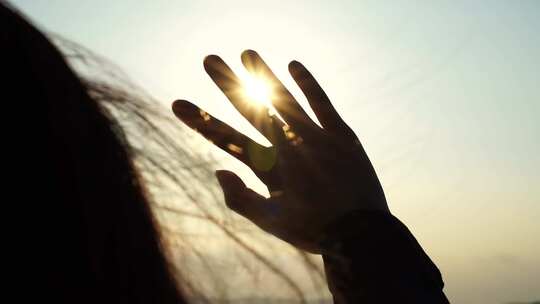 触摸阳光伸手遮挡阳光透过指缝日出人物背影
