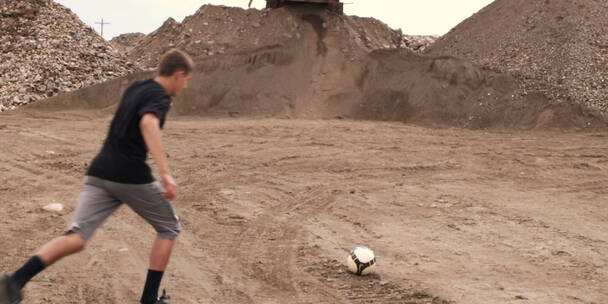 在泥地里踢足球的男孩