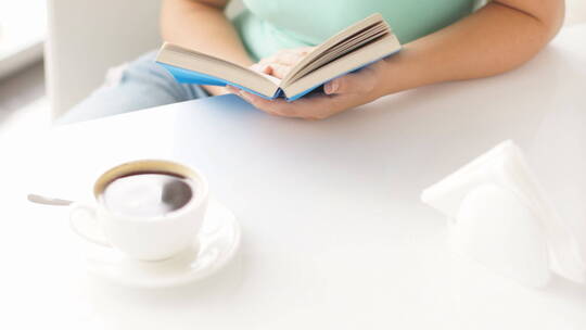 女孩坐在书桌前看书喝咖啡