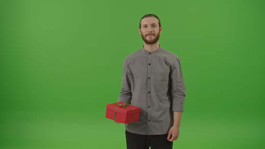 精力充沛的胡须男子展示右手拿着绿色蝴蝶结的红色礼品盒