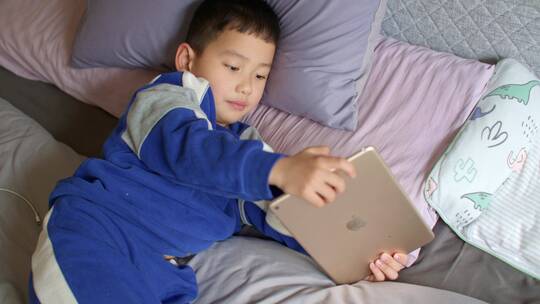 小孩在床上玩平板电脑