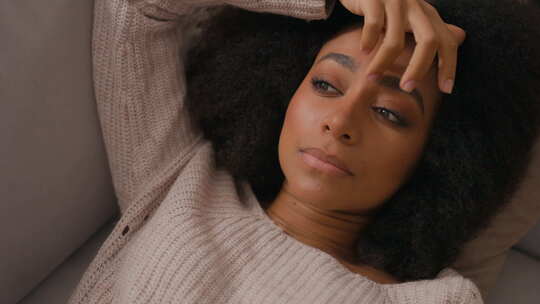 孤独悲伤沮丧的非裔美国女人独自在家躺在沙