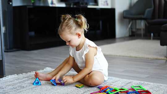 小女孩在家玩彩色磁铁塑料块套件