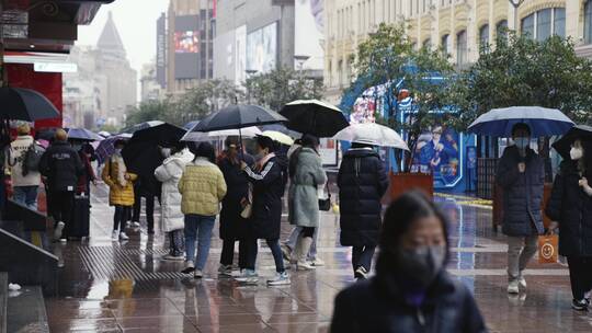 下雨天上海南京路行人撑伞走过拥挤繁忙倒影