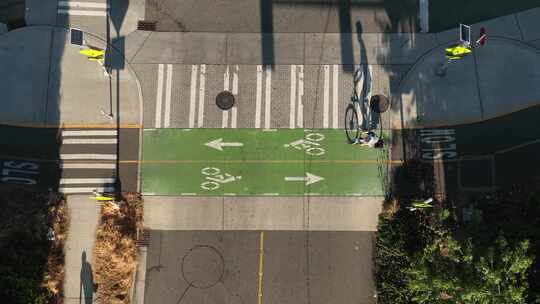 一个骑自行车的人在使用指定的自行车道时通过十字路口的鸟瞰图。视频素材模板下载