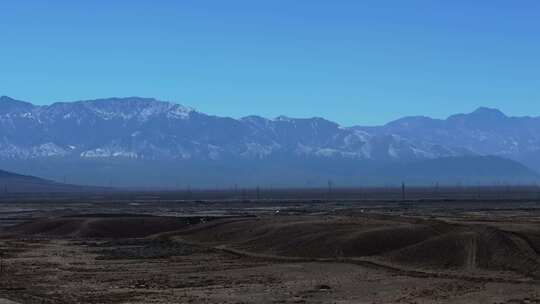 大气航拍西北戈壁滩上的公路及远方的雪山