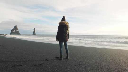 冰岛火山黑沙滩上漫步的女游客