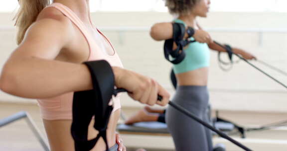 一群女人专注于锻炼，在健身房的划船机上锻