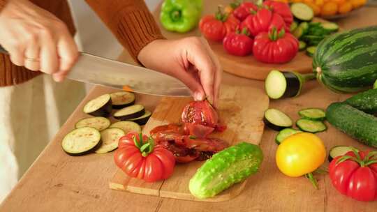 女人用刀切新鲜的生蔬菜西红柿黄瓜在木板上