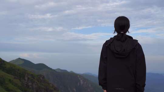 女性青年站在山顶看风景背影看远山感受自然