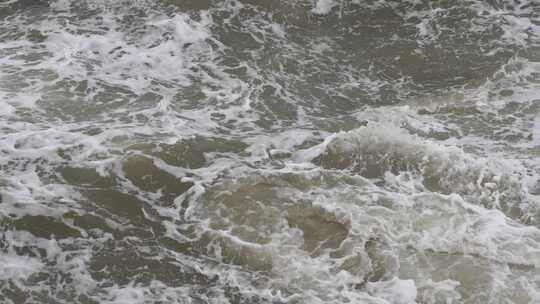 海浪拍打岩石浑浊海水冲刷礁石浪花阴天大海