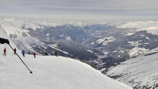 滑雪者的时间流逝，在法国阿尔卑斯山的斜坡/滑雪道上滑雪，后面是白雪皑皑的山谷。