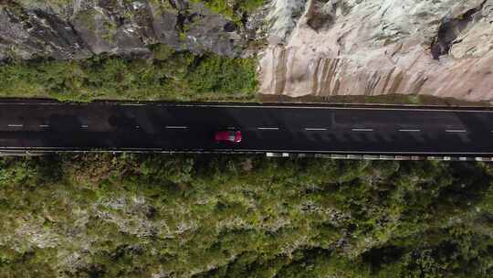 在岩石山坡天线旁边的道路上行驶的汽车