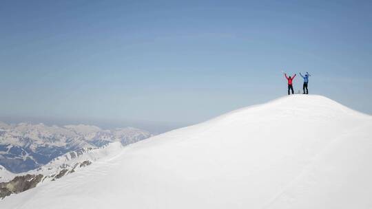 登山者盘登到顶峰拥抱欢呼庆祝胜利