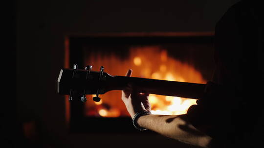 年轻人坐在壁炉旁弹吉他