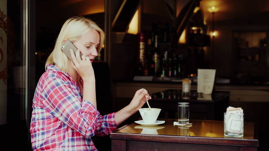 女人边打电话边搅拌咖啡