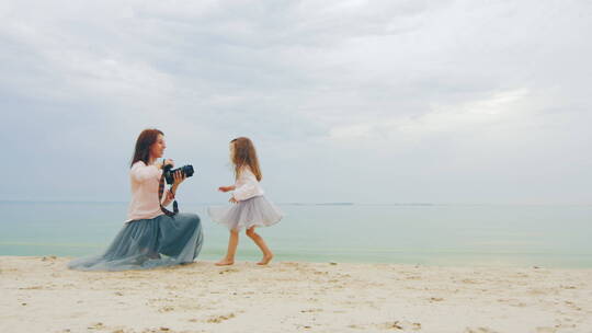 母亲拍摄女儿在海滩上的照片