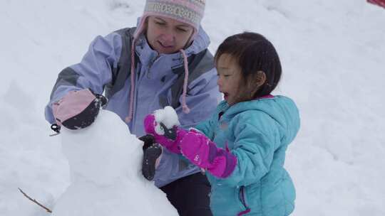 女人和一个小女孩堆雪人