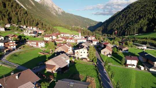 日落阿尔卑斯山绿色山谷中奥地利村庄的鸟瞰图视频素材模板下载