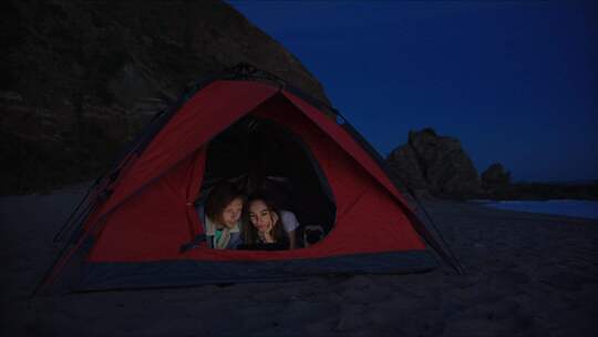 躺在海滩帐篷里用平板电脑的男人和女人