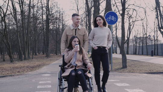 朋友们推着坐轮椅的女孩散步视频素材模板下载