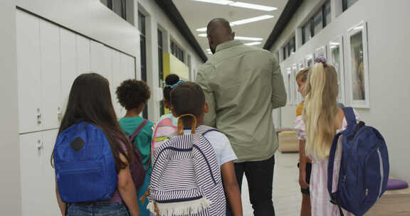 非裔美国男教师和不同学生在学校大厅散步的背影视频