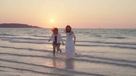 两个女人快乐的在海边奔跑