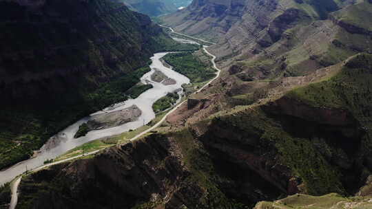 蜿蜒的河流穿过山峡的鸟瞰图，有道路和茂盛