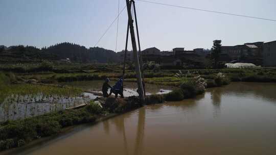 航拍水田里面安装电线杆