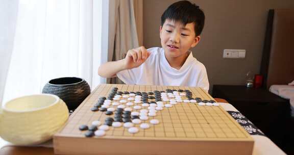 可爱的男孩在窗边下围棋