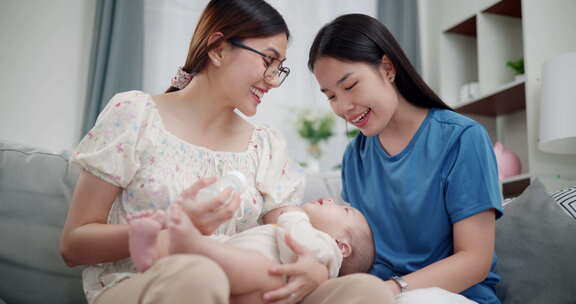 两个年轻的亚洲女人在家里开心地和一个婴儿