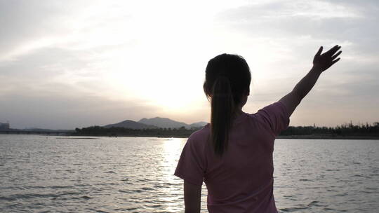 夕阳下中国女性运动后在河边喝水