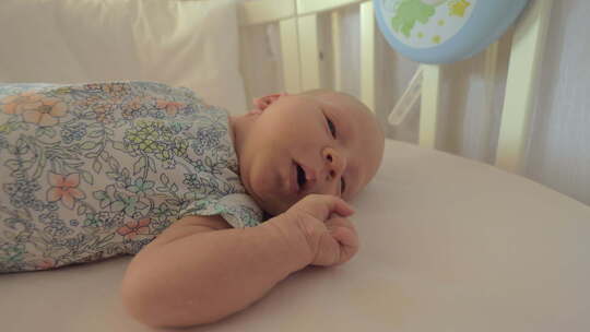 白天睡觉前婴儿床里的新生女孩