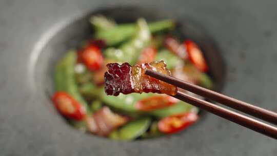 筷子夹起一片腊肉美食特写