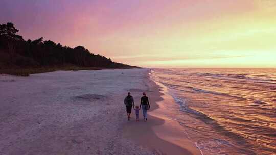 一家人日落时在海滩上散步