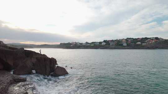 一个渔夫在岸边的剪影，背景是海浪和日出