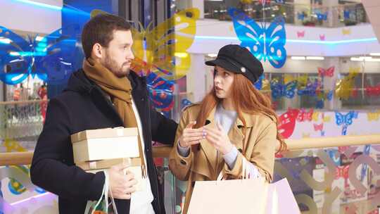 购物狂年轻夫妇在购物中心内部讨论购物