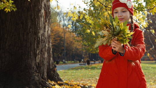 女孩抱着一束秋天的叶子