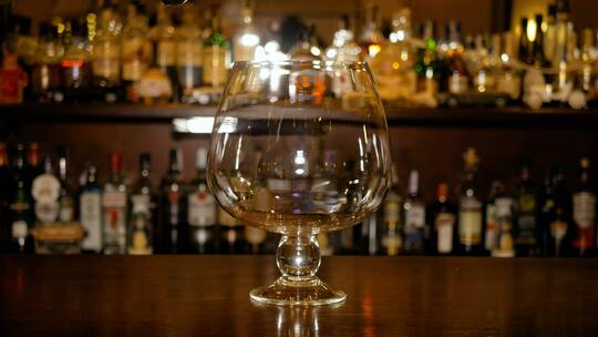 热酒倒入吧台柜背景的大玻璃杯中。
