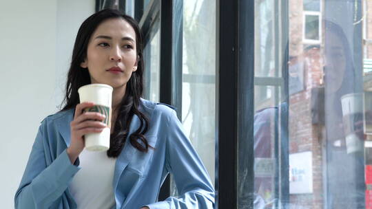 倚在窗边喝奶茶的职员